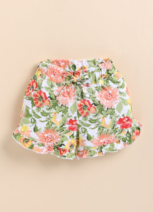 White kids pull-on shorts featuring a lush floral print of peach flowers and green leaves, finished with a matching front tie, side pockets, and sweet ruffled hems