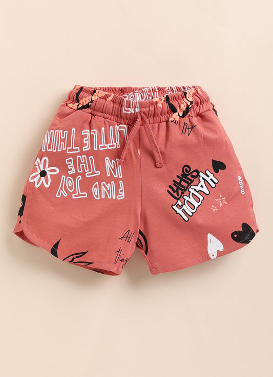 Image file 1409-Peach.jpg showing a pair of Biskid brand peach girls shorts with an elastic drawstring waistband, covered in an all-over beach-themed typography print featuring words like "SWEET" and "COMFORT," with a small "BISKID" brand tag on the side.