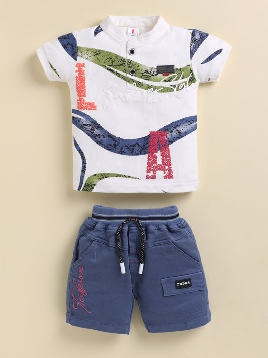 Flat lay of a TODOS brand boys two-piece clothing set featuring a white textured short-sleeve henley shirt with blue and green abstract waves and large red LA letters, paired with blue shorts with a black and white drawstring waist, Fashion embroidered in red on the right leg, and a TODOS logo patch on the left cargo pocket.