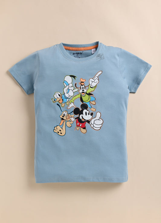 smiling young boy with dark hair modeling a light blue Biskid brand short-sleeve t-shirt. The shirt features a colorful graphic of classic Disney characters including Mickey Mouse, Donald Duck, Goofy, and Pluto in playful poses.