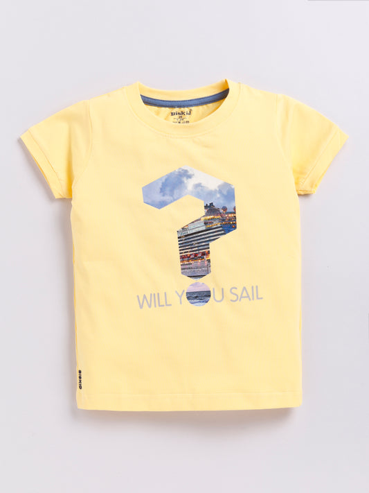 showing a young boy with curly hair modeling a Biskid brand pastel yellow short-sleeve t-shirt. The shirt features a large question mark graphic filled with a photo of a cruise ship, with the dot of the question mark acting as the letter "O" in the text "WILL YOU SAIL" printed below.
