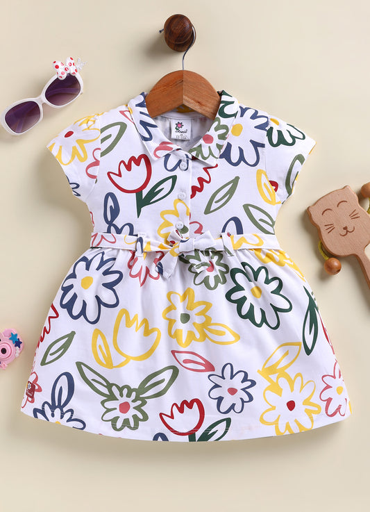 Flat lay of an Annie brand girls short-sleeve white frock featuring a collared neckline front buttons a matching waist tie and a vibrant all-over abstract floral print in forest green navy blue yellow and red.