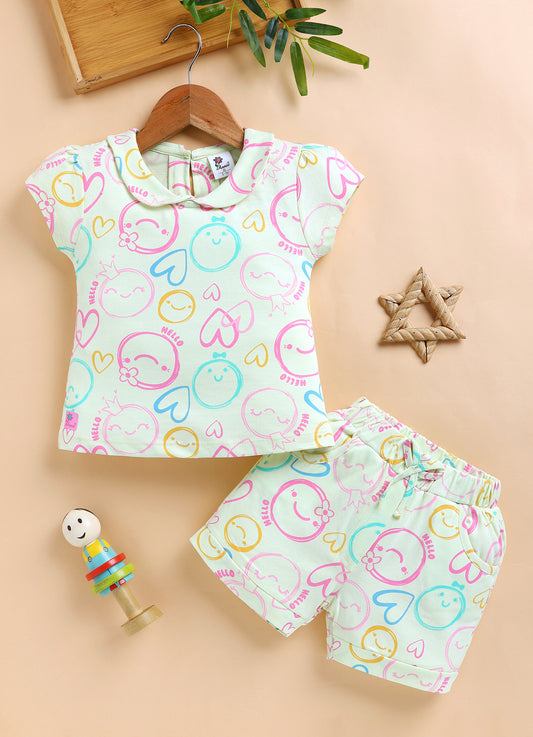 Annie brand girls two-piece clothing set featuring a pale lemon short-sleeve top with a Peter Pan collar and matching shorts. Both pieces feature an all-over pastel print of doodle smiley faces, hearts, and the word HELLO in pink, blue, and yellow. The shorts have an elastic drawstring waist and front pockets.