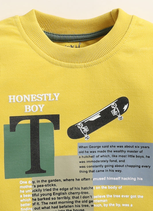 Image file IMG_0281 - Copy.jpg showing a flat lay of a mustard yellow Biskid brand boys long-sleeve sweatshirt featuring "HONESTLY BOY" text and skateboard graphic elements, with a ribbed crew neck, cuffs, and hem.