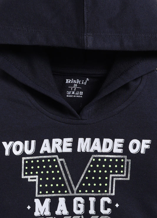 Image file 1756-Blue.jpg showing a flat lay of a navy blue Biskid brand girls hooded sweatshirt featuring the text "YOU ARE MADE OF MAGIC" and associated graphic, displayed with decorative items including children's sunglasses, shoes, and a small toy.
