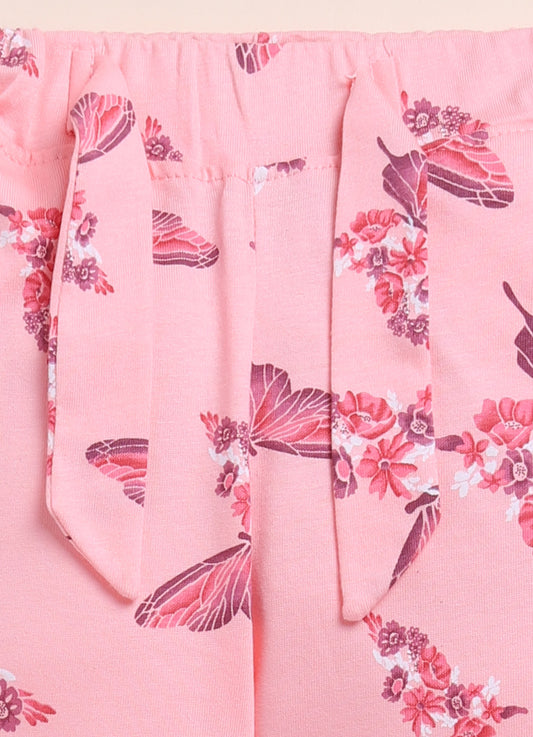 Image file 1512-Peach.jpg showing a pair of Biskid brand girls' peach-colored long pants with an all-over butterfly and floral print, displayed with colorful "GIRL" letter blocks and a bouquet of white flowers.