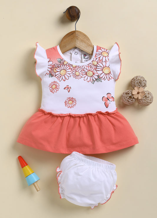 Annie brand girls two-piece frock and panty set. The dress features a white flutter-sleeve bodice with a coral red daisy and butterfly print, a back snap closure, and a solid coral red gathered skirt. It comes with a matching white bloomer panty featuring coral red ruffled trim on the leg openings.