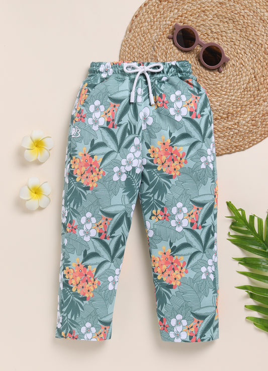 Image file 1511-M.Green.jpg showing a pair of Biskid brand girls mint green joggers with an all-over tropical floral print, featuring an elastic waistband with a white drawstring, displayed with decorative sunglasses, flowers, and greenery.