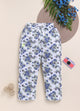 Image file 1511-Navy.jpg showing a pair of Biskid brand girls white joggers with an all-over floral rose print in navy and gray, displayed with a woven mat, blue floral accents, and a toy camera decoration.