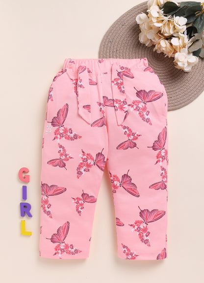 Image file 1512-Peach.jpg showing a pair of Biskid brand girls' peach-colored long pants with an all-over butterfly and floral print, displayed with colorful "GIRL" letter blocks and a bouquet of white flowers.