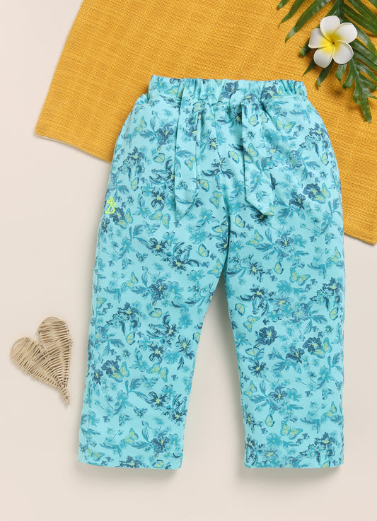 Image file 1512-P.Blue.jpg showing a pair of Biskid brand girls' powder blue long pants with an all-over floral and butterfly print, displayed with flower-shaped sunglasses, two decorative butterfly cutouts, and small blue floral accents nearby.