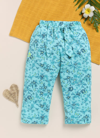 Image file 1512-Sea Green.jpg showing a pair of Biskid brand girls' sea green long pants with an all-over floral and butterfly print, displayed with a heart-shaped wicker decoration and a tropical leaf with a white plumeria flower.