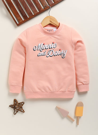 Image file 1754-Lightpeach.jpg showing a Biskid brand girls light peach fleece sweatshirt with "Minnie and Daisy" lettering on the front, displayed on a wooden hanger with decorative star and ice cream-shaped accents nearby.
