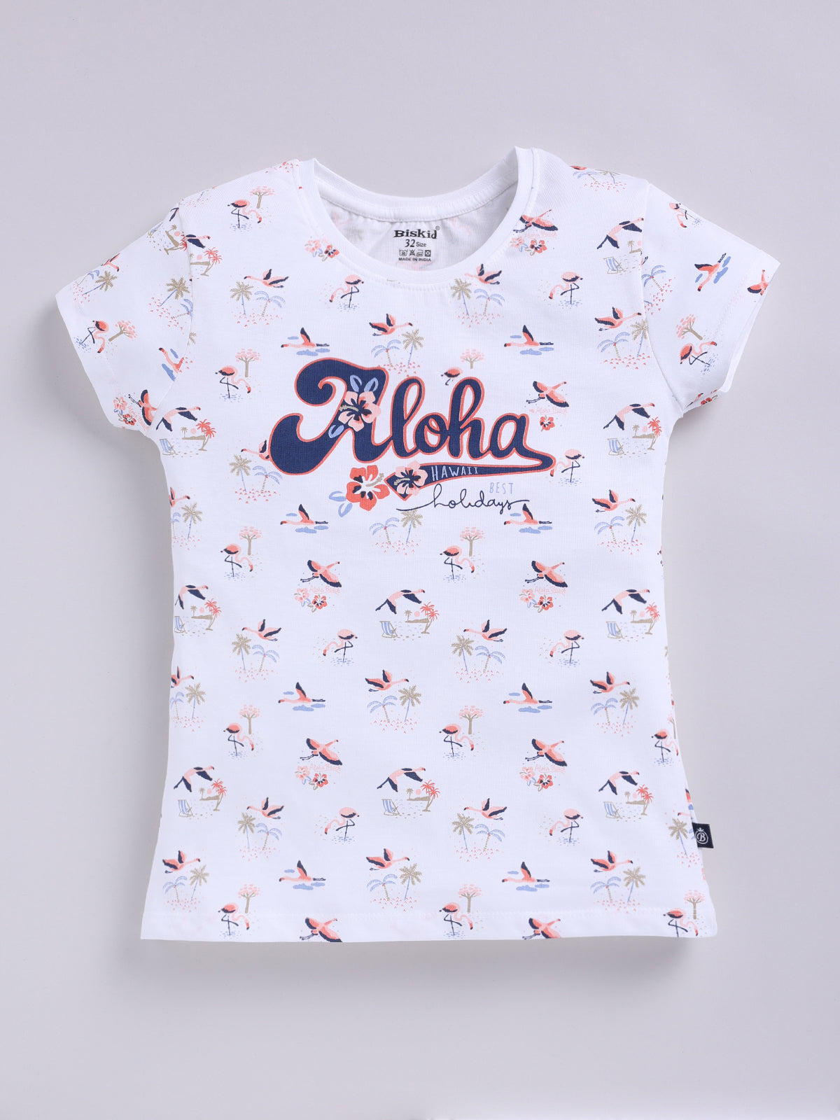 White.jpg showing a flat lay of a white Biskid brand girls short-sleeve t-shirt with an all-over flamingo and palm tree print and "Aloha Hawaii" graphic text on the front.