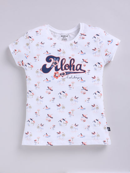 White.jpg showing a flat lay of a white Biskid brand girls short-sleeve t-shirt with an all-over flamingo and palm tree print and "Aloha Hawaii" graphic text on the front.