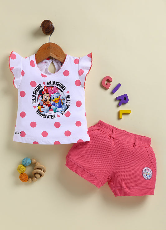 Flat lay of an Annie brand girls two-piece clothing set featuring a white flutter-sleeve top with pink polka dots and a Minnie Mouse and Daisy Duck Hello Summer graphic paired with bright pink textured shorts featuring front pockets belt loops and a small character patch on the left leg.