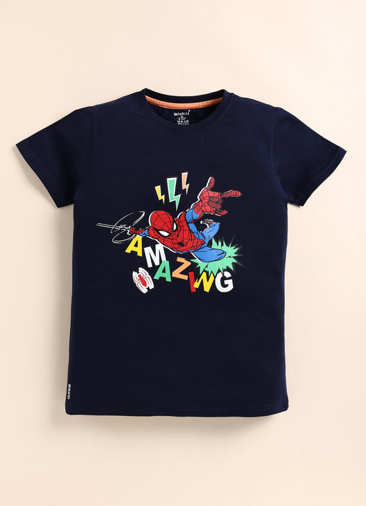 showing a smiling young boy with dark hair modeling a navy blue Biskid brand short-sleeve t-shirt. The shirt features an action graphic of Spider-Man leaping, surrounded by lightning bolts, a white spider symbol, and the word "AMAZING" in scattered, colorful block letters.