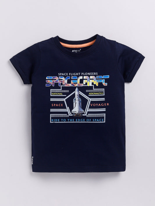 showing a young boy with curly hair modeling a Biskid brand navy blue short-sleeve t-shirt. The shirt features a space-themed chest graphic with a space shuttle, the word "SPACECRAFT" in colorful textured letters, and the text "SPACE FLIGHT PIONEERS" and "RIDE TO THE EDGE OF SPACE".