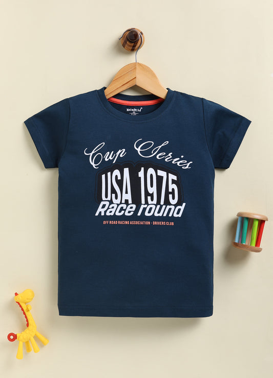 Image file 877-Blu--877-Rust.jpg showing a 2-pack of Biskid boys short-sleeve t-shirts featuring graphic prints, including a rust-red tee with "Discovery Expedition" circular graphics and a navy blue tee with "Cup Series USA 1975" typography.