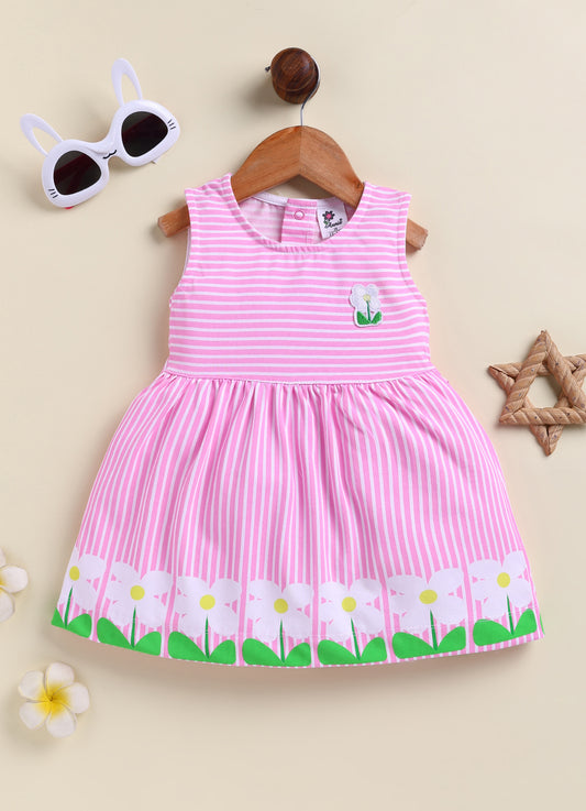 Flat lay of an Annie brand girls sleeveless pink and white striped frock featuring a small flower patch on the chest and a border of large white flowers with green leaves along the bottom hem.