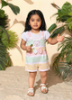 Annie brand girls short-sleeve jumpsuit designed to look like a textured white top underneath pastel green, yellow, and pink striped overall shorts. The outfit features an embroidered pink bear face on the chest, a decorative striped bow, and a back snap closure.