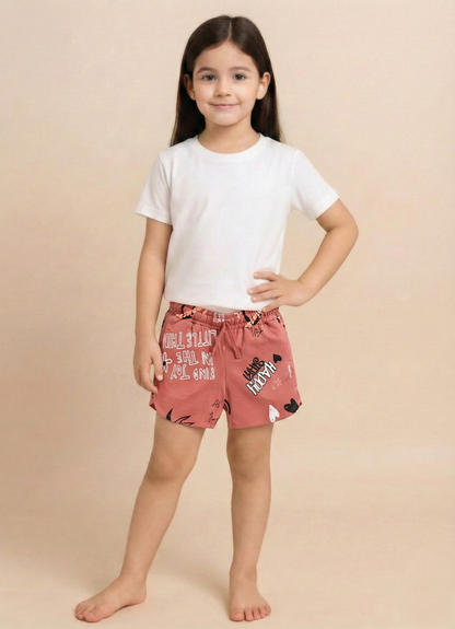 Image file 1409-Peach.jpg showing a pair of Biskid brand peach girls shorts with an elastic drawstring waistband, covered in an all-over beach-themed typography print featuring words like "SWEET" and "COMFORT," with a small "BISKID" brand tag on the side.