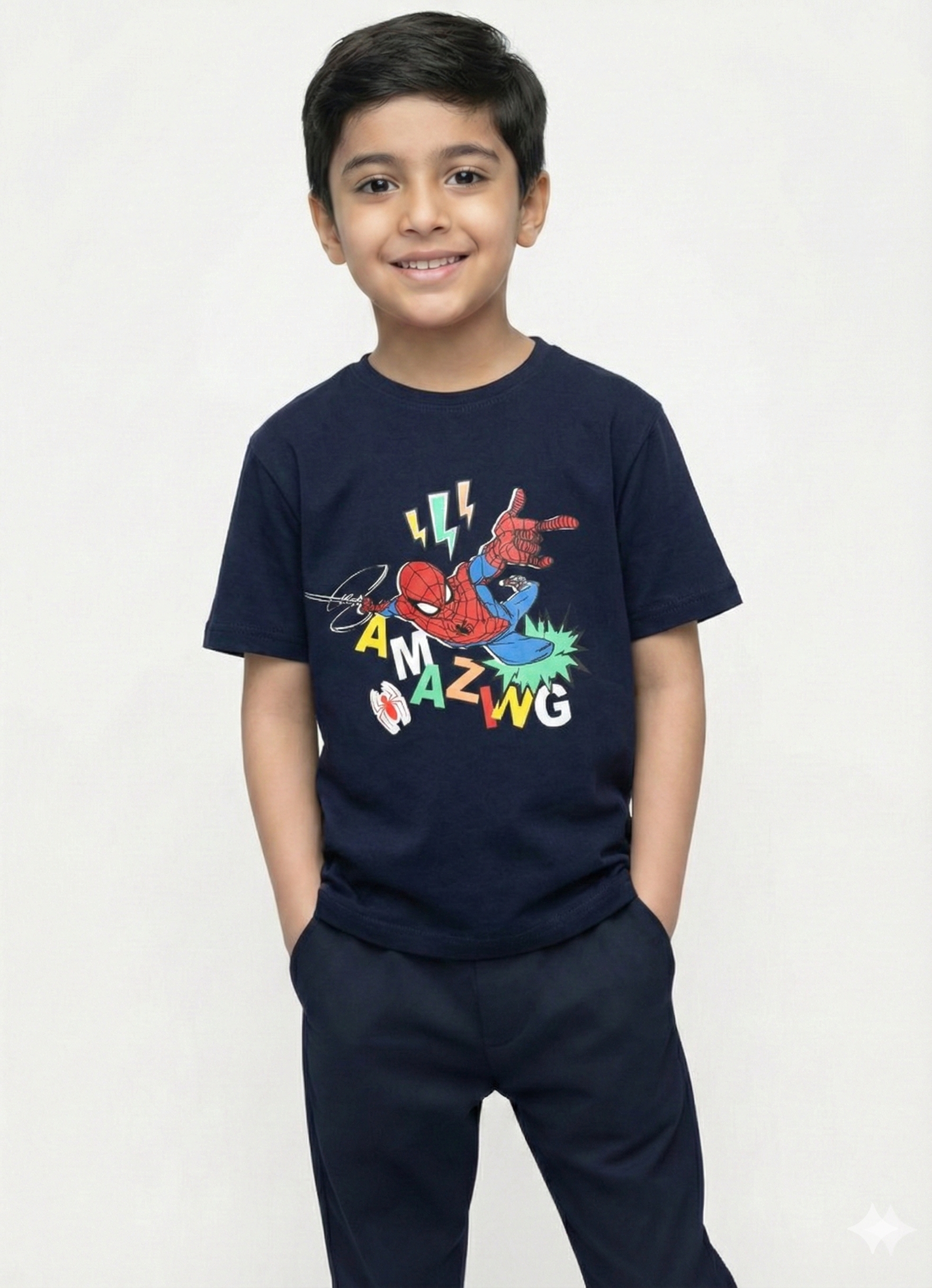 showing a smiling young boy with dark hair modeling a navy blue Biskid brand short-sleeve t-shirt. The shirt features an action graphic of Spider-Man leaping, surrounded by lightning bolts, a white spider symbol, and the word "AMAZING" in scattered, colorful block letters.