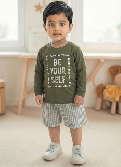 Image file Gemini_Generated_Image_ijt6gaijt6gaijt6.jpg showing a young boy wearing an olive green Biskid brand boys long-sleeve t-shirt with a "Be Your Self" graphic on the chest, paired with gray checkered shorts and white sneakers.