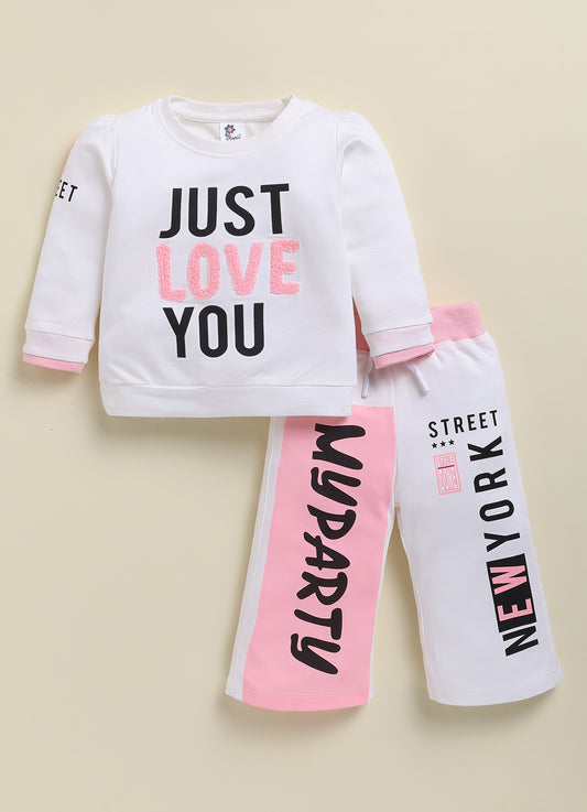 Annie white and pink sporty clothing set for girls featuring a long-sleeve sweatshirt with a "Just Love You" graphic and matching jogger pants with color-blocked details and text prints.