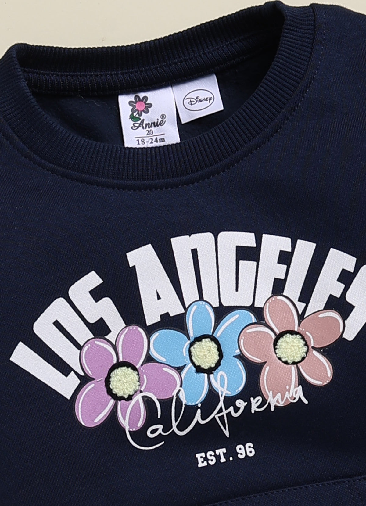 Annie navy blue Los Angeles graphic sweatshirt and jogger clothing set for girls featuring a floral typography print, a Minnie Mouse outline on a kangaroo pocket, and matching printed sweatpants.
