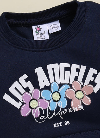 Annie navy blue Los Angeles graphic sweatshirt and jogger clothing set for girls featuring a floral typography print, a Minnie Mouse outline on a kangaroo pocket, and matching printed sweatpants.