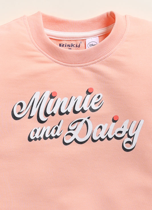 Image file 1754-Lightpeach.jpg showing a Biskid brand girls light peach fleece sweatshirt with "Minnie and Daisy" lettering on the front, displayed on a wooden hanger with decorative star and ice cream-shaped accents nearby.