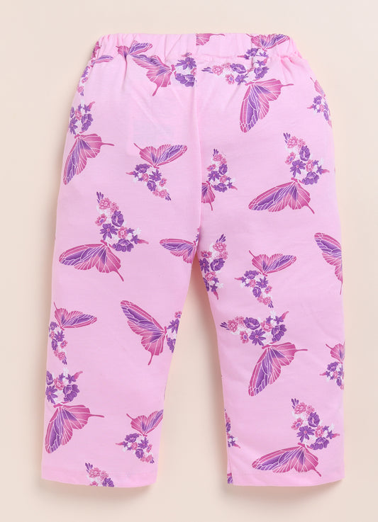 Image file 1512-Pink.jpg showing a pair of Biskid brand girls' pink long pants with an all-over butterfly and floral print, displayed with two star-shaped decorations and a cluster of pink flowers on a woven mat.