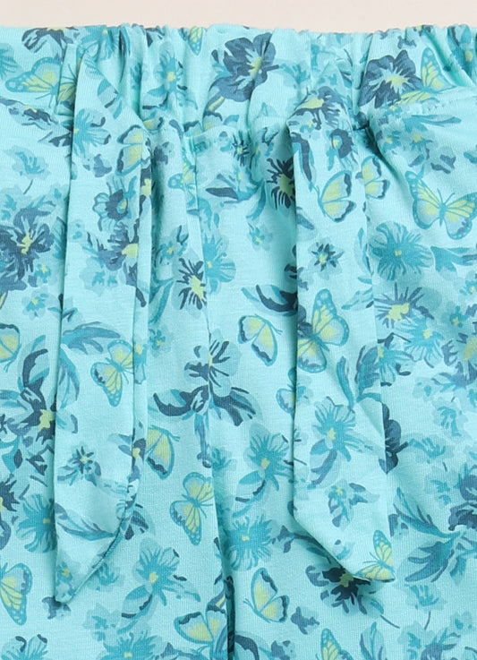Image file 1512-P.Blue.jpg showing a pair of Biskid brand girls' powder blue long pants with an all-over floral and butterfly print, displayed with flower-shaped sunglasses, two decorative butterfly cutouts, and small blue floral accents nearby.