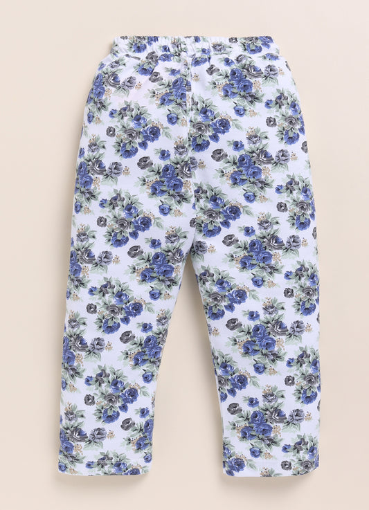 Image file 1511-Navy.jpg showing a pair of Biskid brand girls white joggers with an all-over floral rose print in navy and gray, displayed with a woven mat, blue floral accents, and a toy camera decoration.