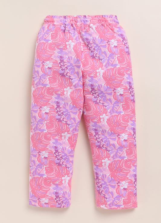 Image file 1511-Pink.jpg showing a pair of Biskid brand girls pink joggers with an all-over tropical leaf print, displayed with fun decorative accents like a rainbow, a unicorn sticker, and flower-shaped sunglasses.