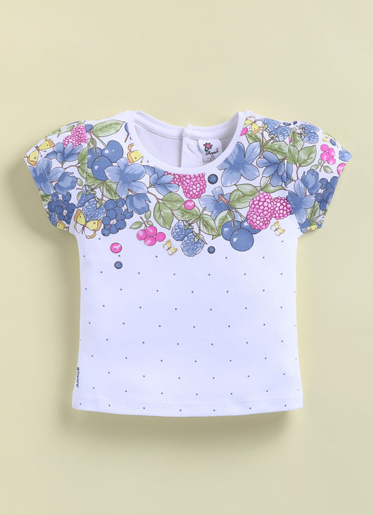 Flat lay of an Annie brand girls two-piece clothing set featuring a white short-sleeve top with a blue floral and berry print across the chest and scattered blue dots paired with textured blue shorts with an elastic tie waist white side piping and a pink cherry patch on the left leg.