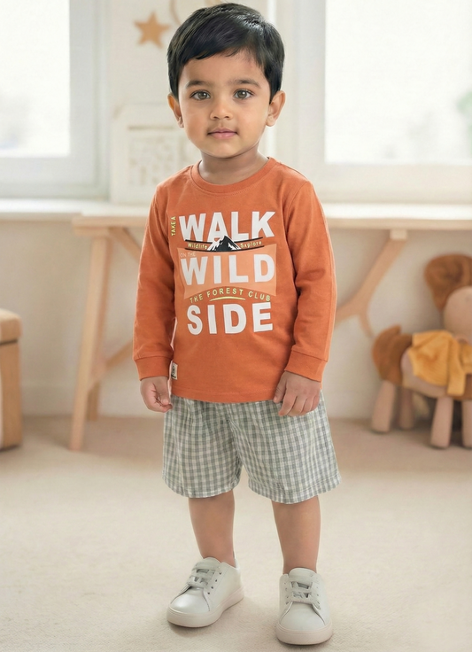 Image file Gemini_Generated_Image_pobj3hpobj3hpobj.jpg showing a young boy wearing a rust-orange Biskid brand boys long-sleeve t-shirt with a "Walk on the Wild Side" forest graphic on the chest, paired with gray checkered shorts and white sneakers.