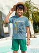 Image file 877-P.Blue.jpg showing a Biskid brand boys' powder blue crew neck t-shirt with a "Board Rebels" comic-style skater graphic on the front, displayed on a wooden hanger with a toy camera and colorful "GAME" letter blocks nearby.
