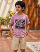 Image file unnamed (37).jpg showing a young boy wearing a Biskid brand mauve/lilac crew neck t-shirt with a "Sun Life" sunset graphic, styled with beige casual shorts.