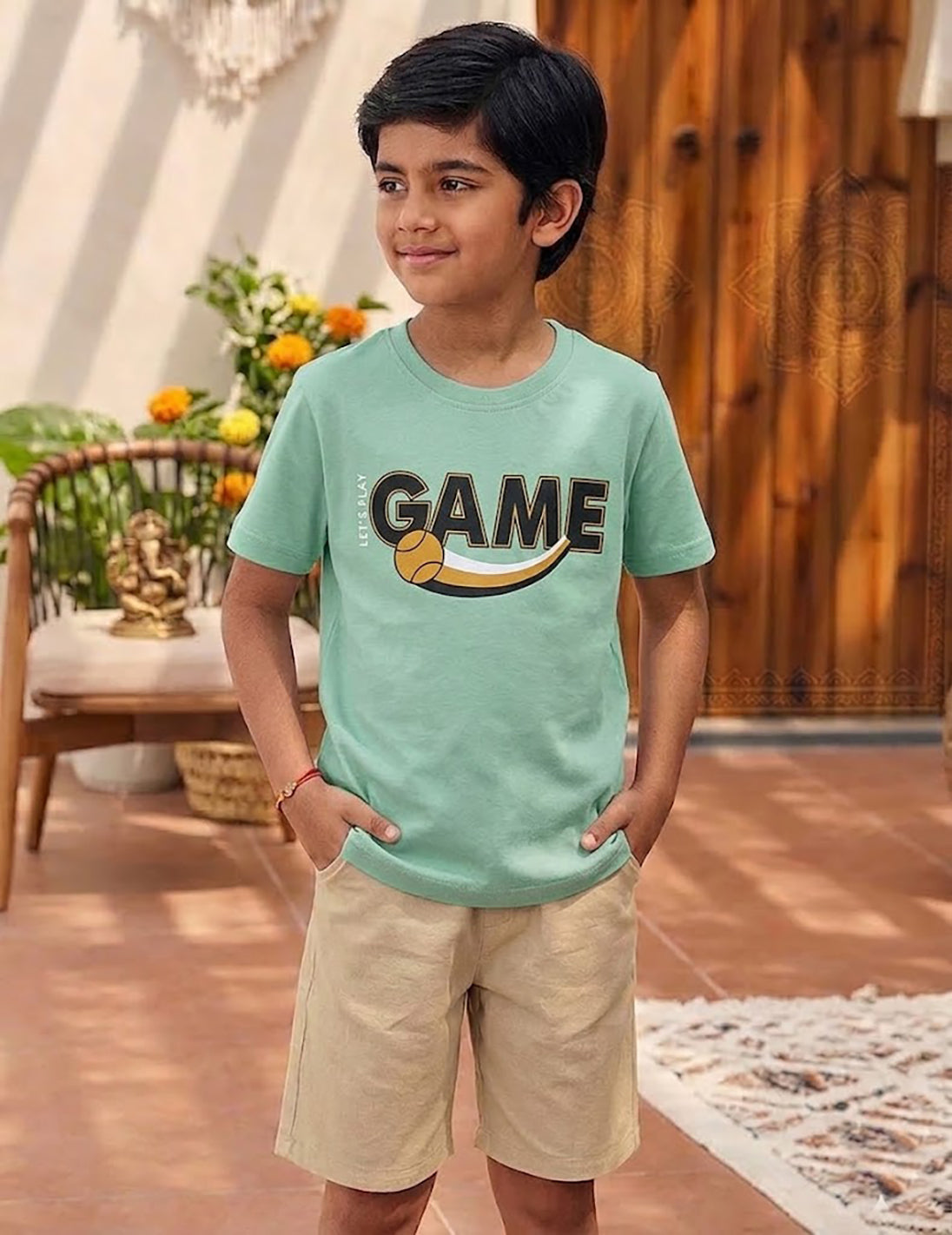Image file unnamed (38).jpg showing a young boy wearing a Biskid brand mint green crew neck t-shirt with a bold "GAME" graphic, styled with beige casual shorts.